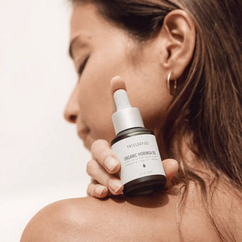 Woman applying Treelogy Organic Moringa Oil to her shoulder, showcasing natural skincare with cold-pressed seed oil.