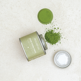 Open tin of Treelogy Moringa Powder with spilled vibrant green powder showing freshness and minimal eco-packaging.