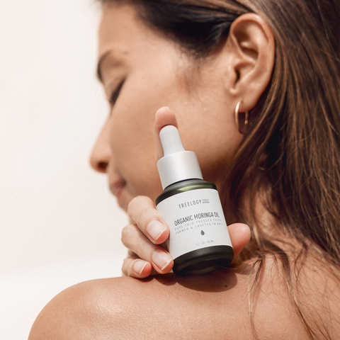 LANG:ID|Seorang wanita mengaplikasikan Treelogy Organic Moringa Oil di bahunya, menampilkan perawatan kulit alami dengan minyak biji cold-pressed.