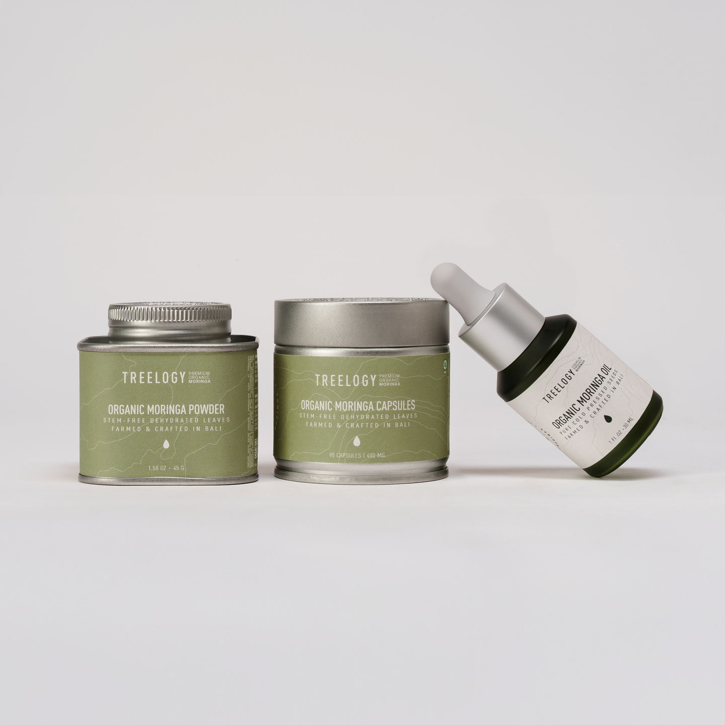 Produk skincare Treeology yang terdiri dari kemasan tin, jar, dan botol dropper, ditata rapi di atas latar belakang abu-abu muda