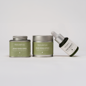 Produk skincare Treeology yang terdiri dari kemasan tin, jar, dan botol dropper, ditata rapi di atas latar belakang abu-abu muda