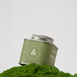 Treelogy Organic Moringa Powder tin resting on a mound of vivid green powder — stem-free, gently dehydrated leaves for maximum nutrient density.