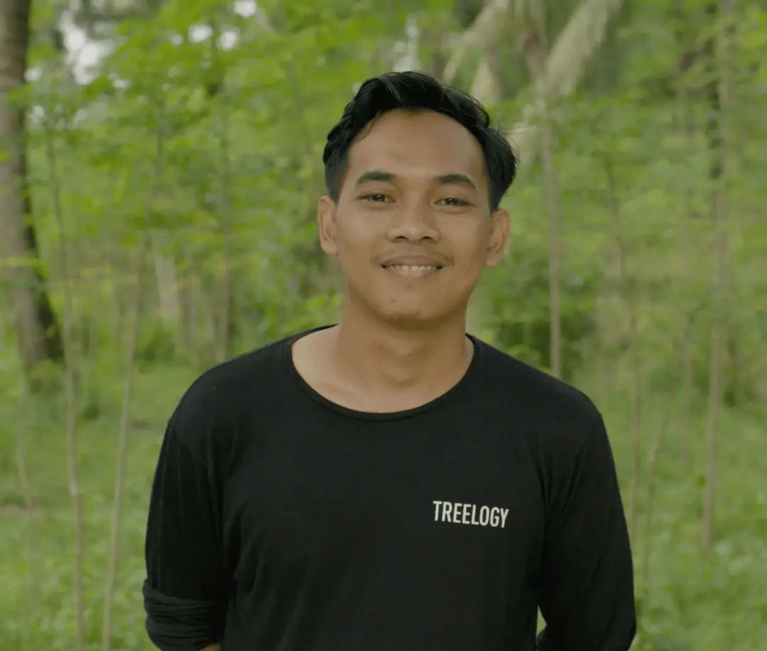 Fery Kurniawan standing outside with trees and greenery in the background.