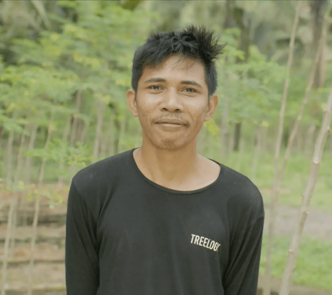 I Kadek Pande Suastika smiling outdoors with lush greenery in the background.