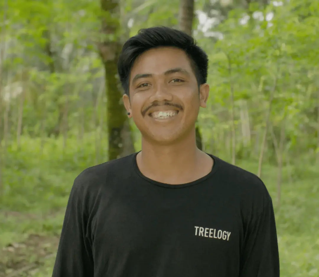 I Ketut Suatra smiling while standing outside with a natural green background.