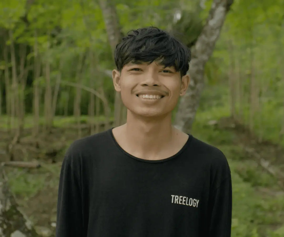 I Komang Adi Ariasa standing outdoors with trees and plants in the background.
