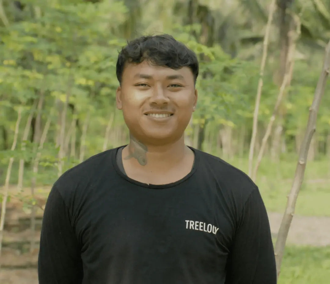 Nyoman Bingin standing outside with a backdrop of trees and lush greenery.
