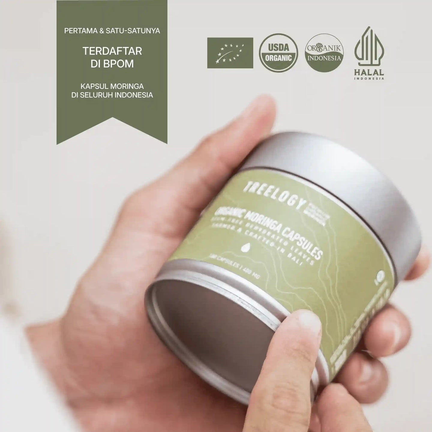 Treelogy Moringa Capsules dengan sertifikasi USDA Organic, Halal, dan BPOM, dipegang tangan untuk menonjolkan keaslian produk.